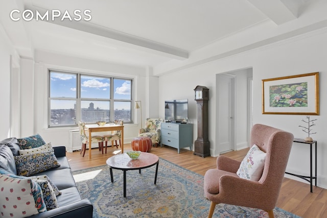 living room featuring beamed ceiling, light wood-style flooring, radiator heating unit, and baseboards