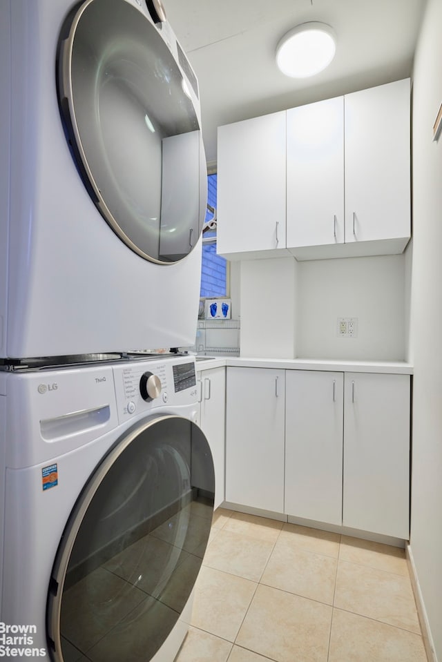 117 E 72nd St Unit 2W, New York City, NY 10021 - washroom featuring stacked washer / dryer, cabinet space, and light tile patterned floors