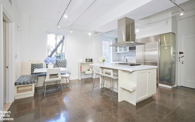 117 E 72nd St Unit 2W, New York City, NY 10021 - kitchen with island exhaust hood, breakfast area, a kitchen island, light countertops, and a breakfast bar