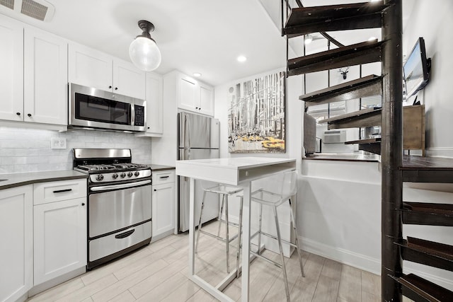 211 Thompson St Unit Lb, New York City, NY 10012 - kitchen featuring dark countertops, white cabinetry, stainless steel appliances, and tasteful backsplash