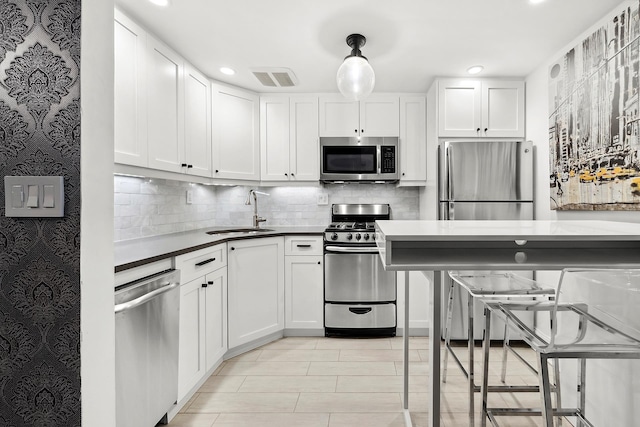 211 Thompson St Unit Lb, New York City, NY 10012 - kitchen featuring appliances with stainless steel finishes, backsplash, a sink, white cabinetry, and visible vents