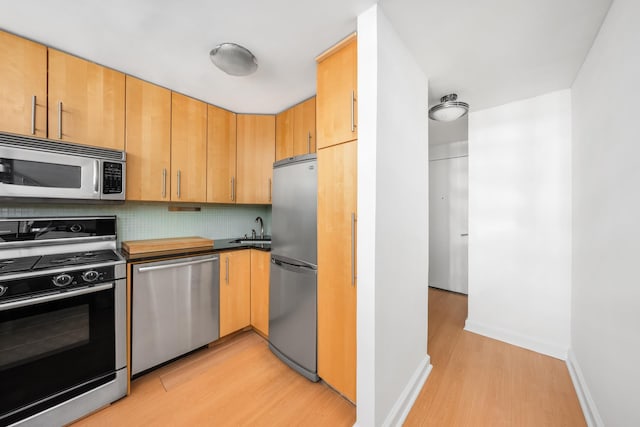 211 Thompson St Unit Lb, New York City, NY 10012 - kitchen with a sink, stainless steel appliances, tasteful backsplash, light wood-style flooring, and baseboards