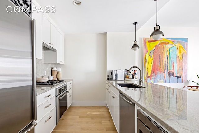 kitchen featuring stainless steel appliances, a sink, light wood-type flooring, and white cabinets