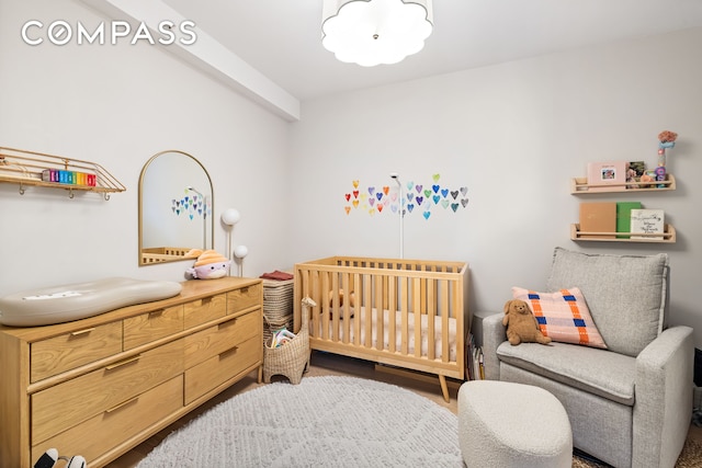 bedroom with a nursery area and wood finished floors