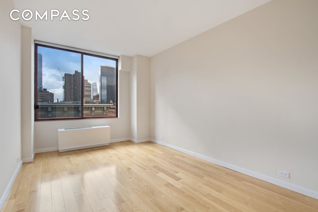 393 W 49th St Unit 6G, New York City, NY 10019 - spare room with wood finished floors, radiator, and baseboards
