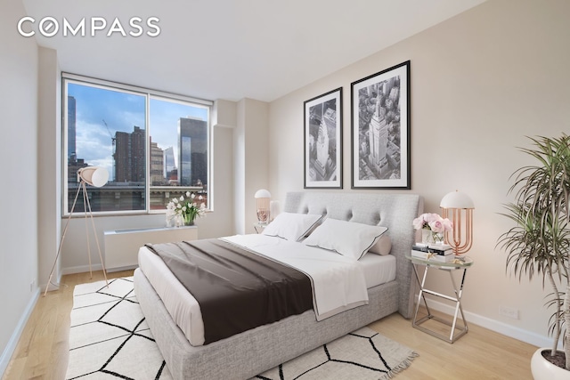 393 W 49th St Unit 6G, New York City, NY 10019 - bedroom featuring wood finished floors, baseboards, and a city view