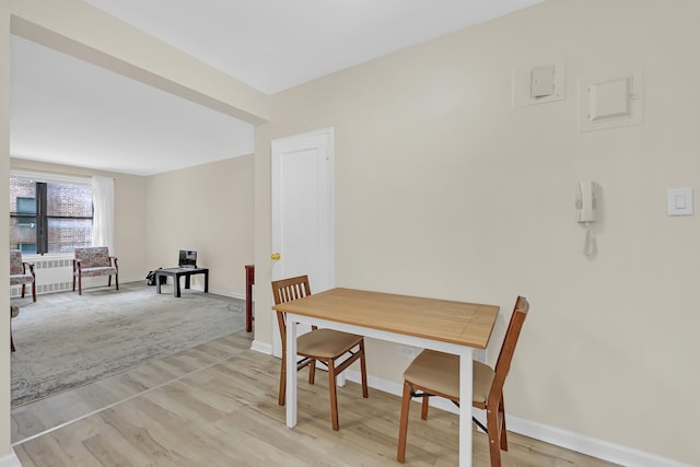 dining room with radiator, light wood-style floors, and baseboards