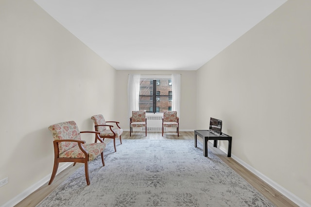 sitting room featuring baseboards, wood finished floors, and radiator