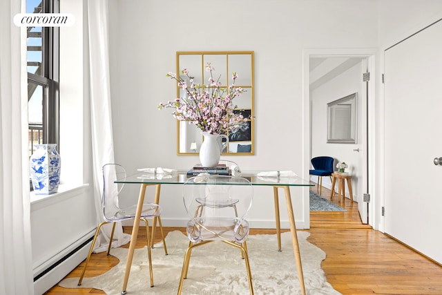 dining space with wood finished floors and a baseboard heating unit