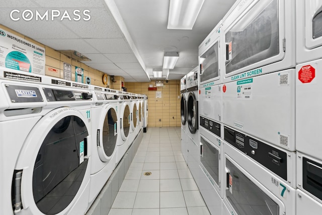 communal laundry room with stacked washer / dryer, separate washer and dryer, light tile patterned flooring, and tile walls