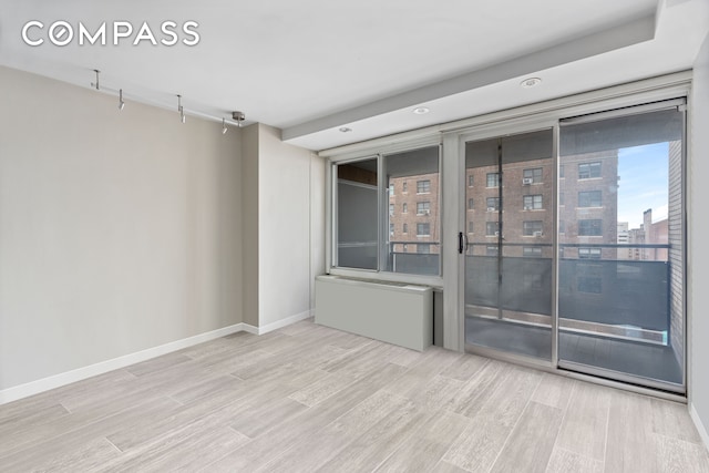 empty room featuring wood finished floors, baseboards, a city view, and recessed lighting
