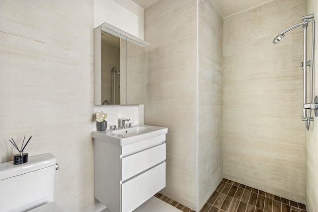 full bath featuring tile walls, a tile shower, vanity, and toilet