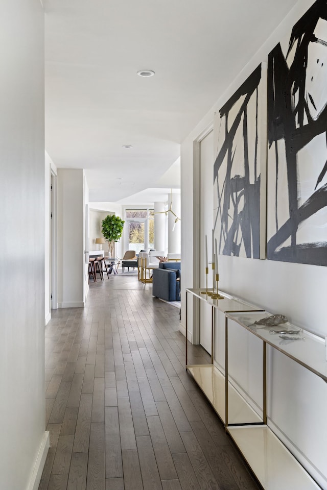 hallway featuring vaulted ceiling, baseboards, and dark wood-style flooring