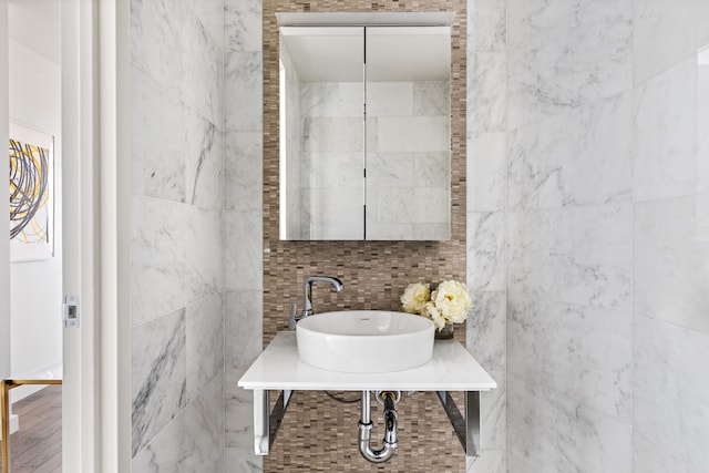bathroom with a sink and tile walls