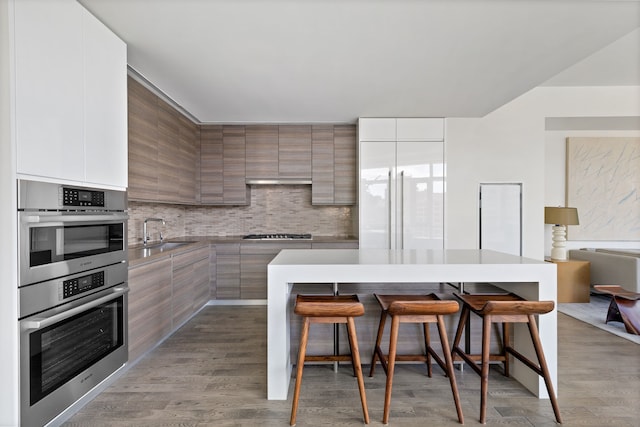 kitchen featuring modern cabinets, a kitchen breakfast bar, a sink, and stainless steel appliances
