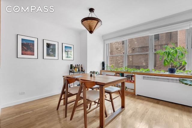 251 E 32nd St Unit 2A, New York City, NY 10016 - dining space with radiator heating unit, light wood-type flooring, and crown molding