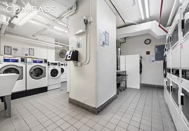 common laundry area featuring baseboards, tile patterned flooring, stacked washer and clothes dryer, and washer and clothes dryer