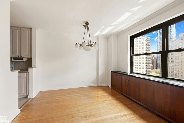 165 W End Ave Unit 17M, New York City, NY 10023 - unfurnished dining area featuring light wood-style floors, a chandelier, a city view, and ornamental molding