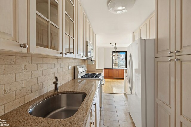 165 W End Ave Unit 17M, New York City, NY 10023 - kitchen featuring cream cabinets, white appliances, light stone countertops, glass insert cabinets, and backsplash