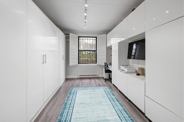 corridor featuring baseboard heating, wood finished floors, rail lighting, and baseboards