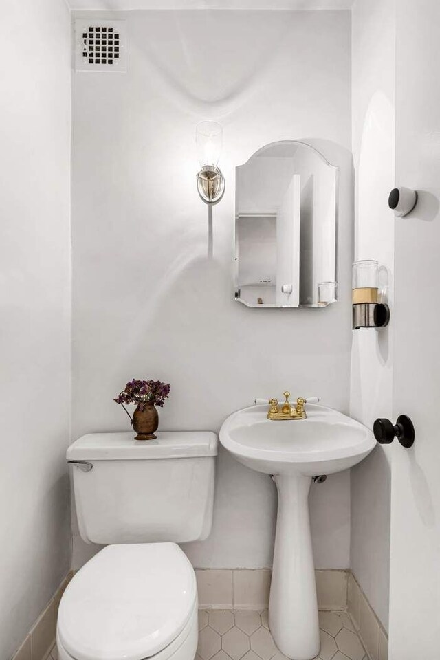 314 E 50th St Unit 1E, New York City, NY 10022 - half bath with toilet, baseboards, and tile patterned flooring