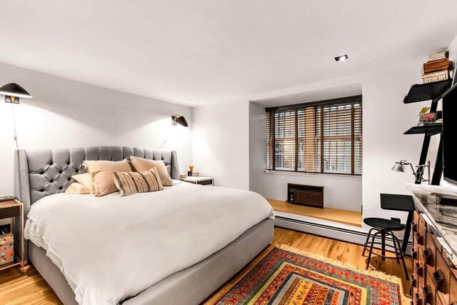 314 E 50th St Unit 1E, New York City, NY 10022 - bedroom with a baseboard heating unit, wood finished floors, and a wall unit AC