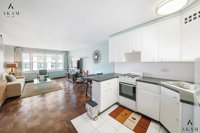 155 E 38th St Unit 9-H, New York City, NY 10016 - kitchen featuring white gas range, dark countertops, a peninsula, and open floor plan