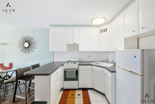155 E 38th St Unit 9-H, New York City, NY 10016 - kitchen featuring white appliances, a sink, a peninsula, and dark countertops