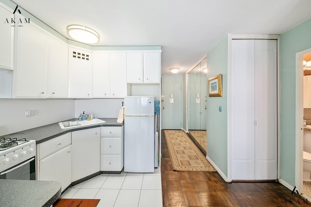 155 E 38th St Unit 9-H, New York City, NY 10016 - kitchen with white appliances, dark countertops, white cabinets, and wood finished floors