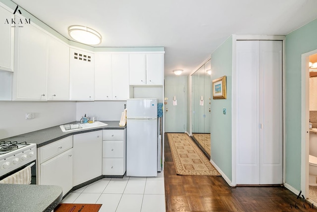 155 E 38th St Unit 9-H, New York City, NY 10016 - kitchen with white appliances, dark countertops, white cabinets, and wood finished floors