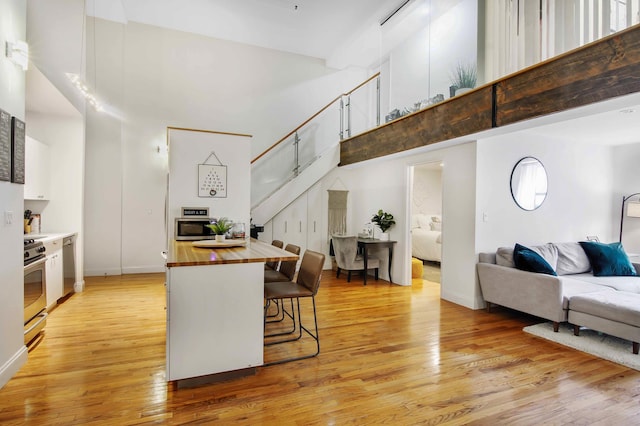 259 21st St Unit 1-C, New York City, NY 11215 - kitchen with a towering ceiling, butcher block counters, appliances with stainless steel finishes, light wood-style flooring, and open floor plan