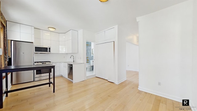 467 Pacific St Unit 18, New York City, NY 11217 - kitchen featuring appliances with stainless steel finishes, white cabinetry, light countertops, modern cabinets, and light wood-style flooring