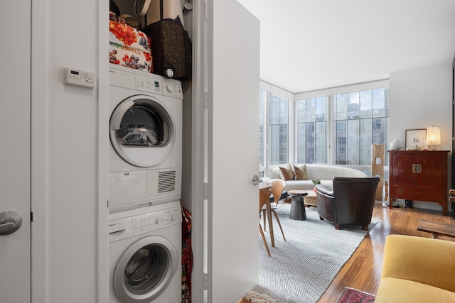 clothes washing area with stacked washer / dryer and wood finished floors