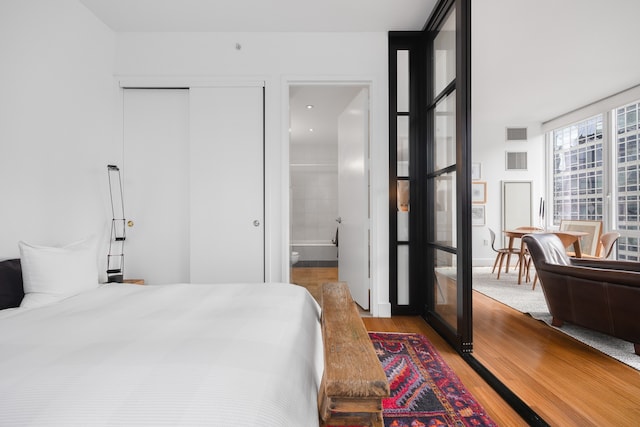 bedroom featuring light wood finished floors and ensuite bathroom
