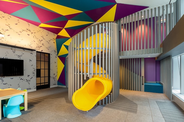 playroom with baseboards, a high ceiling, and wallpapered walls
