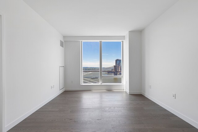 spare room featuring baseboards, dark wood finished floors, and visible vents