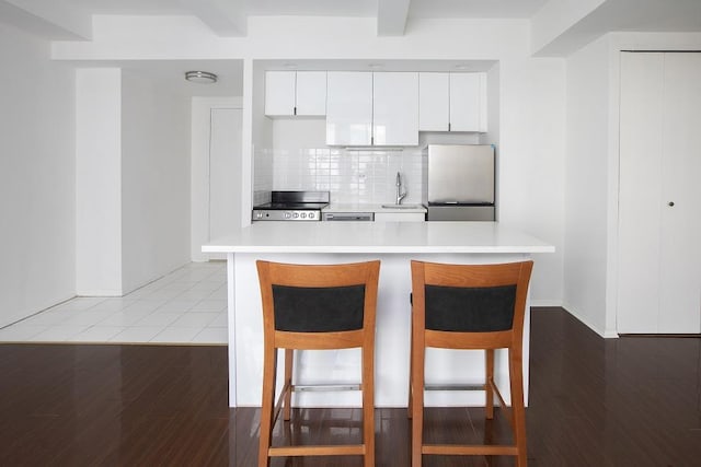 kitchen with a kitchen breakfast bar, a sink, appliances with stainless steel finishes, and light countertops