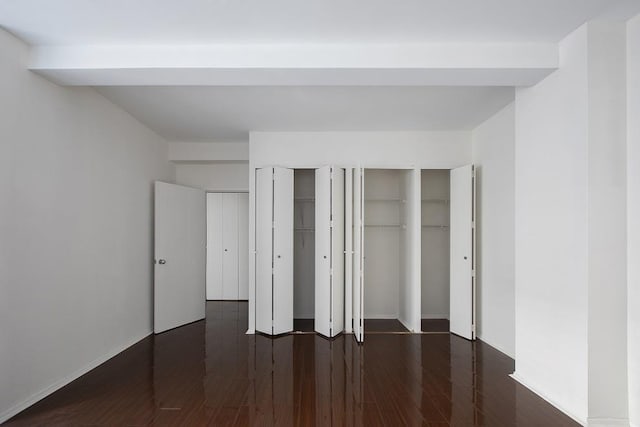 unfurnished bedroom with wood finished floors and multiple closets