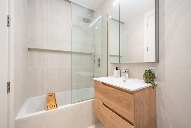 full bath with tiled shower / bath, vanity, and tile walls