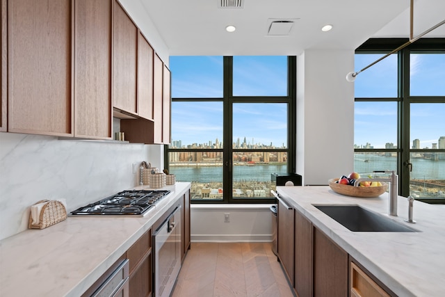 180 Front St Unit 17-E, New York City, NY 11201 - kitchen featuring stainless steel gas stovetop, oven, light stone counters, decorative backsplash, and recessed lighting