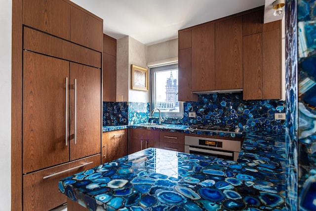 58 W 58th St Unit 30-E, New York City, NY 10019 - kitchen featuring paneled refrigerator, wall oven, backsplash, stainless steel gas stovetop, and dark stone countertops