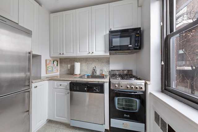 kitchen with light stone counters, a sink, decorative backsplash, appliances with stainless steel finishes, and white cabinetry