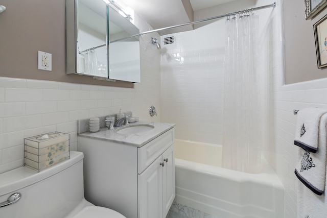 bathroom featuring visible vents, toilet, vanity, tile walls, and shower / bath combo