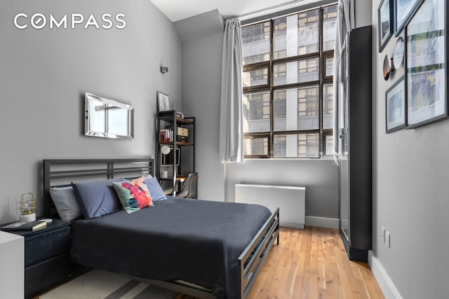 bedroom with multiple windows, baseboards, and light wood-style flooring