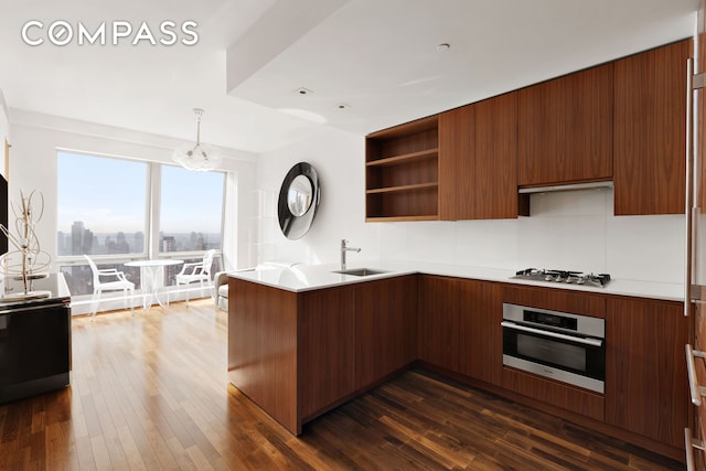 kitchen with stainless steel appliances, modern cabinets, a sink, open shelves, and a peninsula