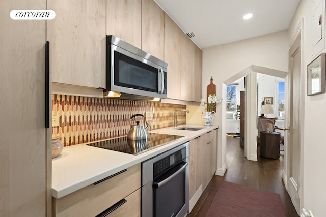 kitchen featuring dark wood-style flooring, light brown cabinets, light countertops, stainless steel appliances, and backsplash