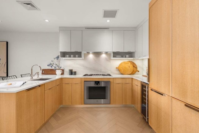kitchen featuring a sink, stainless steel oven, stovetop, a peninsula, and visible vents