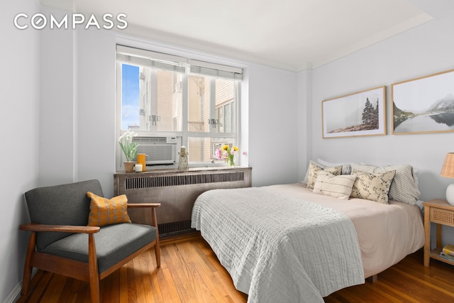 bedroom featuring radiator heating unit, hardwood / wood-style flooring, and cooling unit