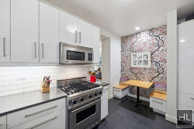 311 W 97th St Unit 3N, New York City, NY 10025 - kitchen with appliances with stainless steel finishes, wallpapered walls, white cabinets, tasteful backsplash, and dark tile patterned floors