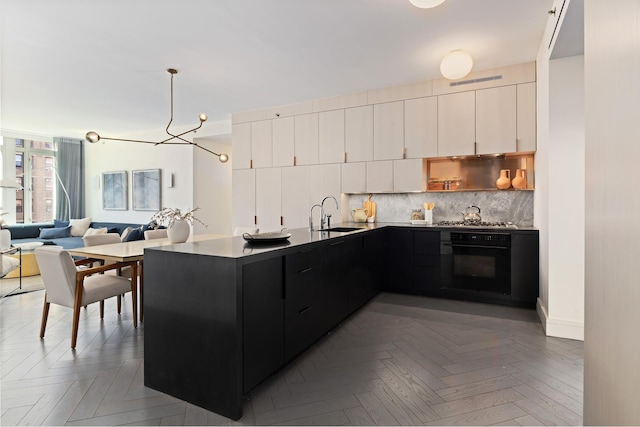 545 W 110th St Unit 6Eg, New York City, NY 10025 - kitchen featuring black oven, dark cabinetry, backsplash, a peninsula, and modern cabinets